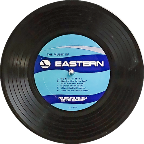 The image shows a vinyl record with a label in the center. The label is blue with white text and features the logo of "EASTERN" at the top. The text on the label is as follows:

    "The Music of EASTERN"
    Below the title, there's a tracklist:
        "Fly Eastern" Theme
        "Number One to the Sun"
        "Air Bus Samba"
        "Americana Journeys"
        "Salute to Latin Horizons"
        "Wings of the Wind"

At the bottom of the label, there is a notice that reads "FOR EMPLOYEE USE ONLY NOT FOR BROADCAST" and the record's speed is listed as "33 1/3 RPM". The record appears to be for internal use by employees of the company rather than for commercial sale or broadcast.