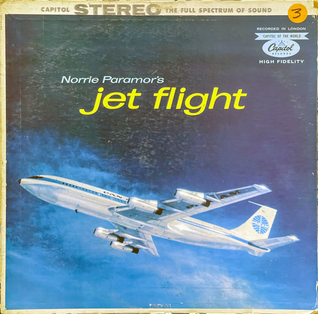 This is a record sleeve for Norrie Paramor's "Jet Flight" album features a vintage aesthetic typical of mid-20th-century design. The top portion of the sleeve is dominated by the "Capitol Stereo" logo, indicating that the record is produced in stereo sound, and boasts of "the full spectrum of sound." Below it, the album's title, "Jet Flight," is written in bold, yellow font that stands out against the darker background.

There's also text indicating that it was "Recorded in London" and sports the "Capitol" of the world branding, referring to Capitol Records' global reach, and "High Fidelity," which refers to high-quality sound reproduction. The Capitol Records logo is placed in the top right corner.

The main visual element is an image of a jet airplane, which is a Boeing 707 in Pan Am livery, mid-flight against a deep blue sky. The airplane is shown in an angled ascent, with the underside visible to the viewer, suggesting the excitement and innovation of jet travel. 

The cover art captures the era's fascination with air travel and the promise of adventure and luxury it represented. The style of the graphics and fonts used for the text also evoke the design sensibilities of the 1950s or 1960s, a period when commercial jet travel was becoming more widespread and popularized.