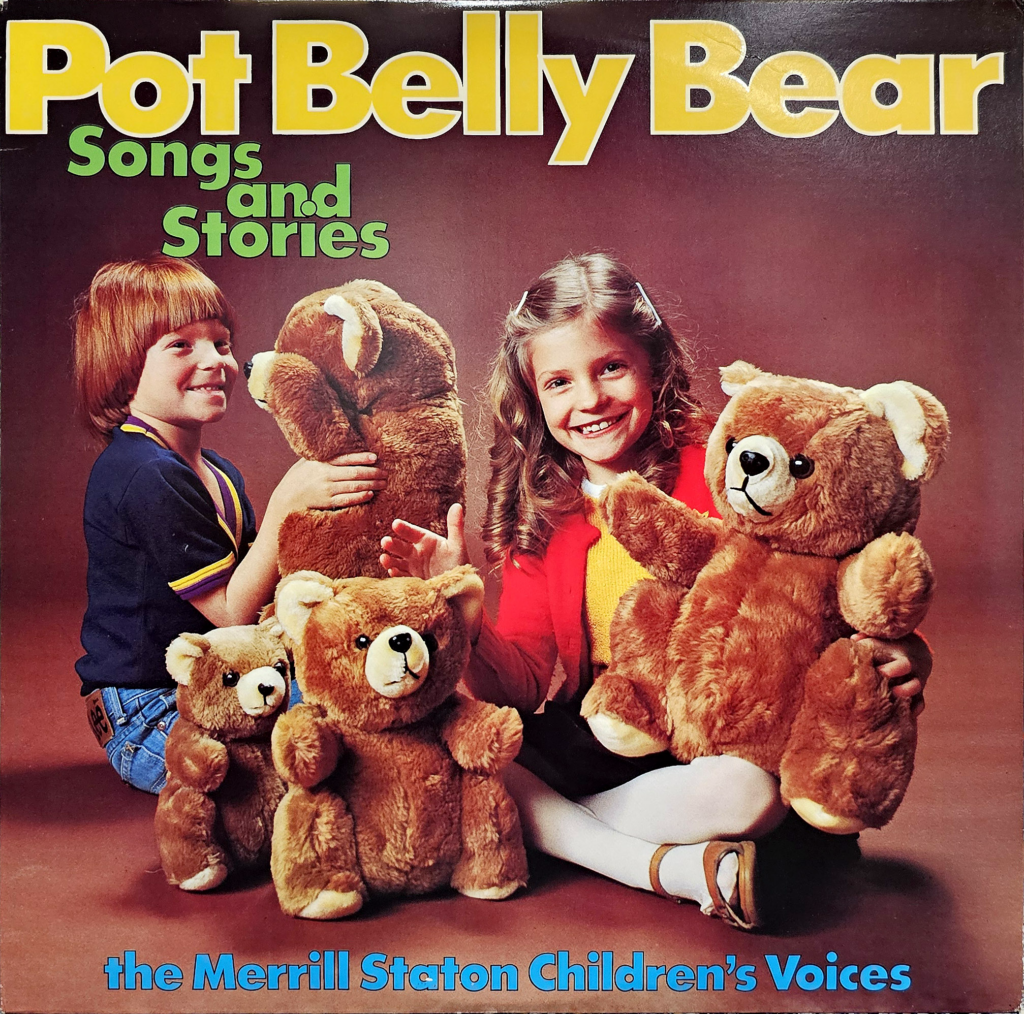 This image shows the front cover of a record sleeve for "Pot Belly Bear Songs and Stories" by the Merrill Staton Children's Voices. The cover features large, bold yellow text on the top against a brown background, announcing the title. Below the title, two smiling children, a girl and a boy, are prominently displayed.

The boy, on the left, is dressed in a blue and yellow outfit with short hair, holding a pot belly bear plush toy in his hands and looking directly at the camera with a wide smile. The girl, on the right, wears a red and yellow outfit with white pants, her long curly hair framing her cheerful face, also holding a pot belly bear and giving a bright, friendly smile.

In front of the children, there are two smaller pot belly bear plush toys, adding to the warm, inviting atmosphere. The text at the bottom of the image credits the music to "the Merrill Staton Children's Voices," suggesting the album features a children's choir.

The overall mood of the cover is playful and engaging, aimed at attracting a young audience with its colorful and cheerful design.