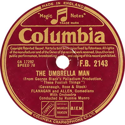 The image shows a vintage Columbia record label for the song "The Umbrella Man." The label is circular and features a maroon background with gold text. The top of the label displays the "Columbia" logo prominently, along with the trademark "Magic Notes." The record number "F.B. 2143" is listed to the right, and below it, the song title "The Umbrella Man" is credited to Cavanaugh, Rose & Stock. The performers are Flanagan and Allen, Comedians, with Orchestra conducted by Ronnie Munro. The label indicates that the record is a 78 RPM and was made in England by Columbia Graphophone Co. Ltd. The bottom of the label also contains rights and publishing information, with the logos for Chappell, Wilhelm Hansen, and BIEM. The overall design reflects the classic style of early 20th-century record labels.