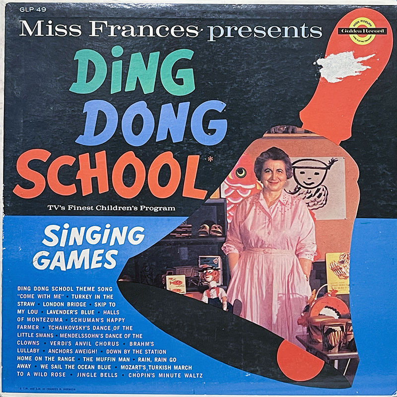 The colorful front cover of Miss Frances Presents Ding Dong School, a 1959 Golden Records LP. The design features bold, playful typography in green, blue, and red for the title. On the right is a full-color cutout photo of Miss Frances in a pink dress, smiling warmly and standing in a classroom surrounded by puppets, books, and children’s artwork. A blue banner across the bottom says “Singing Games” and lists song titles including “Come With Me,” “Lavender’s Blue,” “Brahms’ Lullaby,” “Turkey in the Straw,” and “Mozart’s Turkish March.” The upper right corner has a torn area partially obscuring the Golden Records logo.
