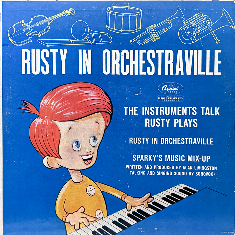 A bright blue album cover featuring a cartoon boy with red hair named Rusty, smiling and playing a piano keyboard. Above him are simple line drawings of orchestral instruments including a violin, drum, trumpet, trombone, and tuba. The text reads “Rusty in Orchestraville,” “The Instruments Talk, Rusty Plays,” and credits Capitol Records. The cover promotes musical stories with talking and singing sound created by Sonovox.