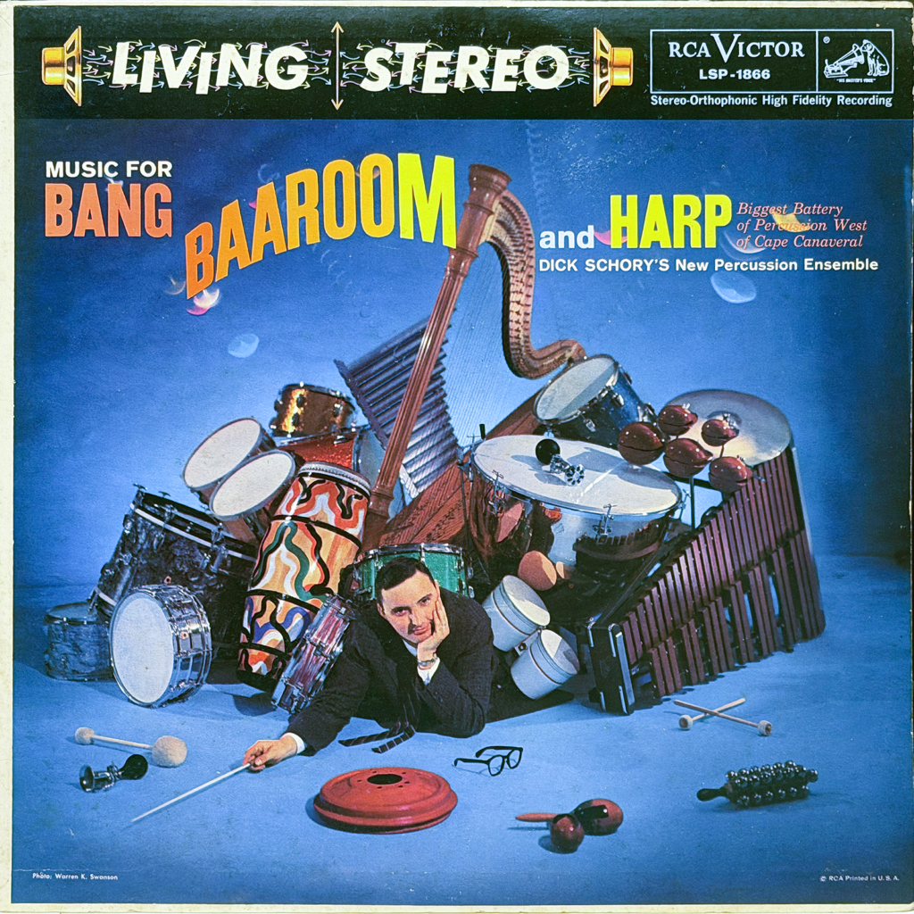 The front cover of the RCA Victor Living Stereo album Music for Bang, Baa-room and Harp by Dick Schory’s New Percussion Ensemble. A bold banner across the top reads “LIVING STEREO” with stylized arrows and speaker icons, alongside the RCA Victor logo and catalog number LSP-1866.

The main image shows a studio scene against a blue background filled with percussion instruments arranged in a loose pile. Visible instruments include multiple drums, bongos, timpani, cymbals, a vibraphone or xylophone, maracas, and a large harp rising prominently near the center. In front of the instruments, a man in a suit lies on his side, propped on one elbow with his head resting in his hand, holding a conductor’s baton. Scattered around him are mallets, drumsticks, and small percussion pieces.

The album title appears in large, colorful text: “BANG” in bold orange, “BAA-ROOM” in oversized yellow letters, and “and HARP” in bright green. Smaller text notes it as the “Biggest Battery of Percussion West of Cape Canaveral.” The overall design is bright, playful, and emphasizes the variety and scale of percussion instruments featured on the recording.
